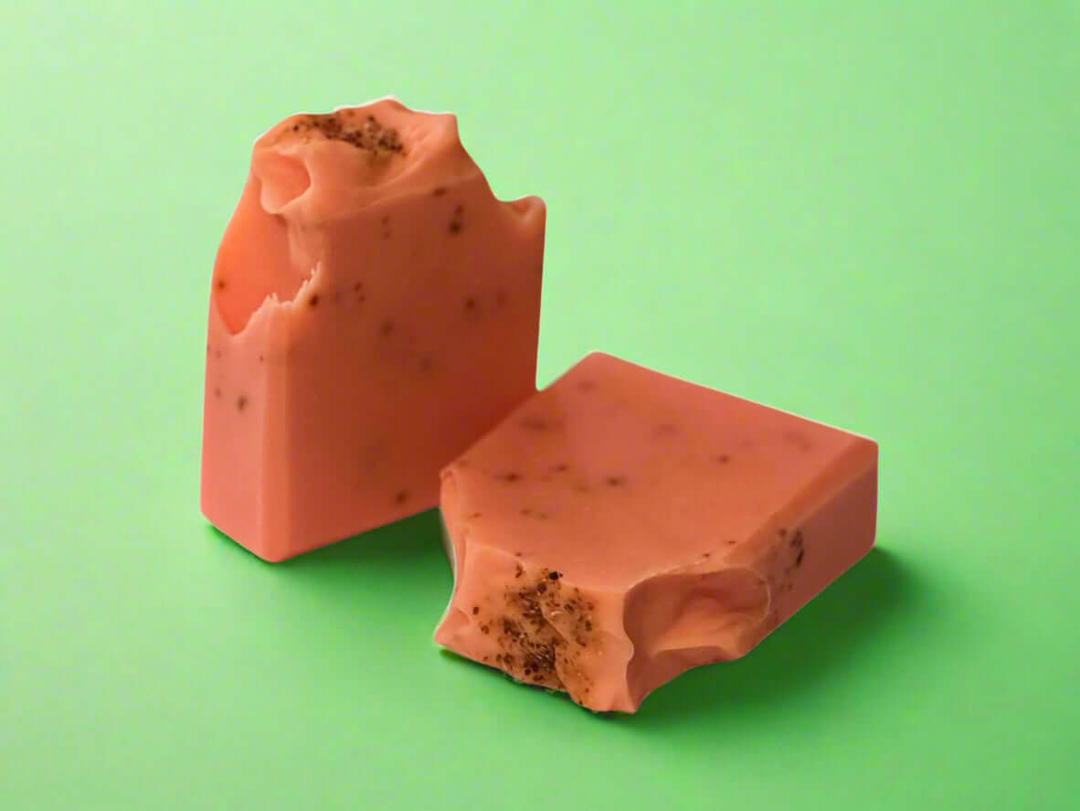 Zest O'Clock artisan soap bars infused with blood orange oil and orange peels on a green background.